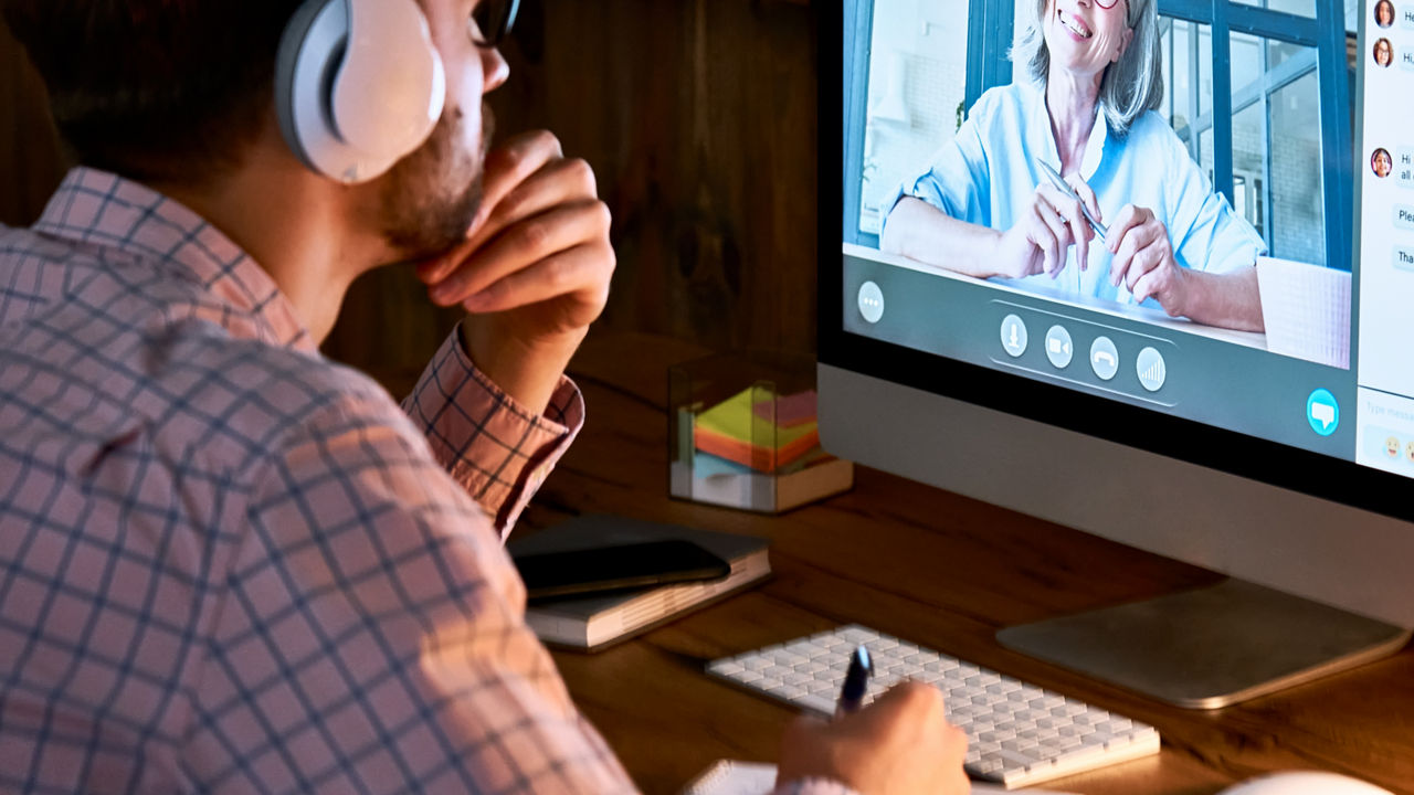 Male student wearing headphones taking online course training, watching webinar, remote seminar university class, virtual learning with social distance web teacher, tutor or coach on computer screen.