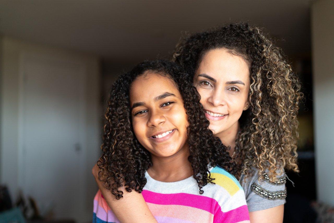 Portrait of mother and daughter embracing at home