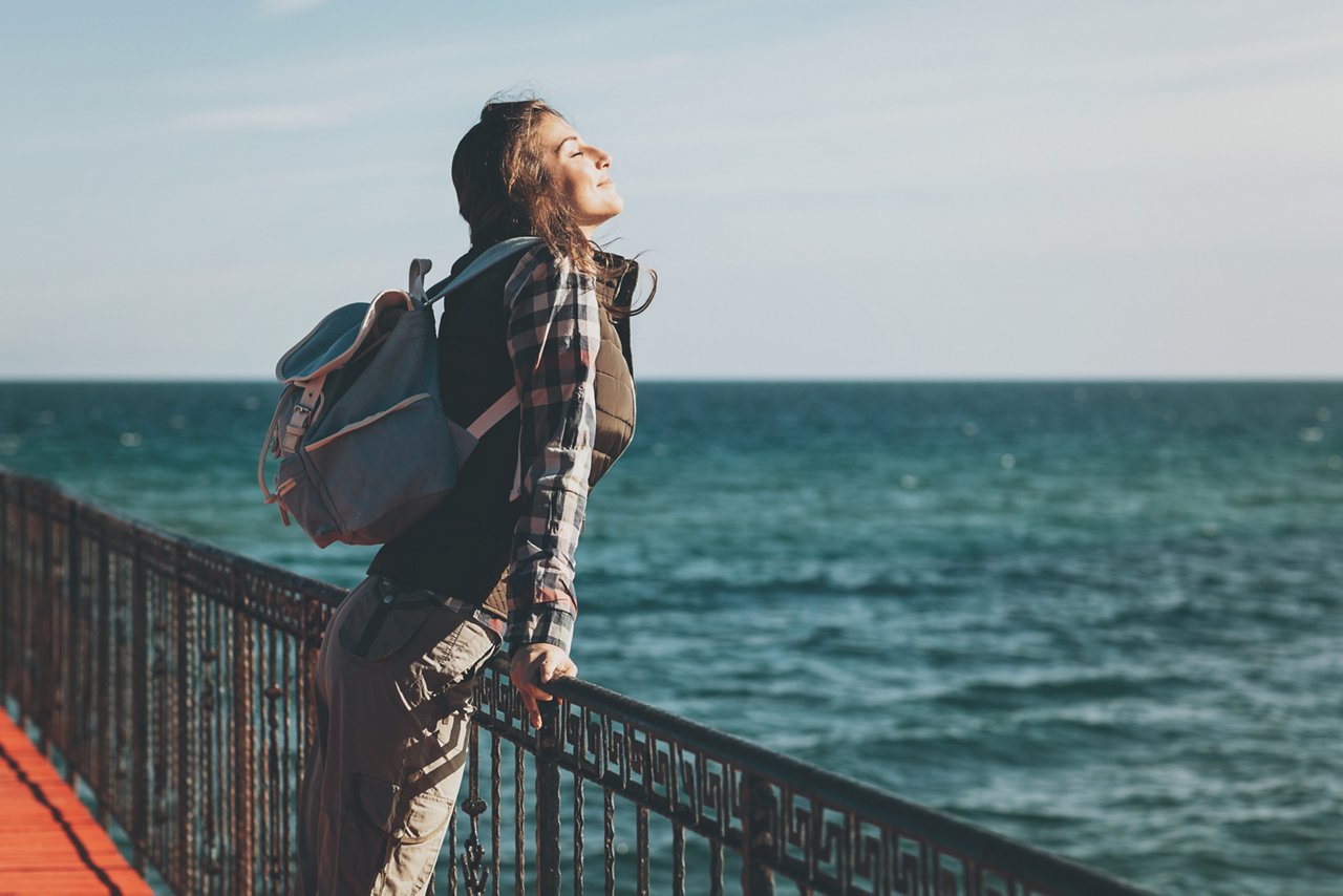 Young woman with eyes closed enjoying the air and sea on a sunny day